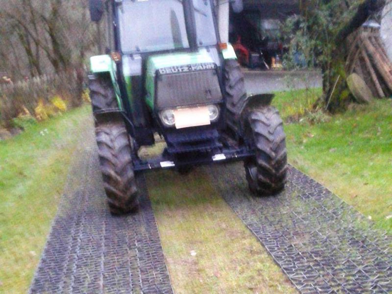 Ein Traktor fährt auf einem mit dem Rasengitter RG24 befestigten Wirtschaftsweg.