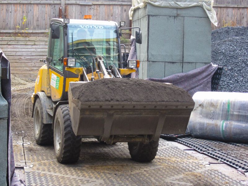 Radlader transportiert Erde über gesicherte Fläche auf dem Tiefgaragendach