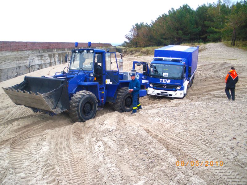 Traktor mit Anhänger meistert sandigen Hang dank Bodenschutz.