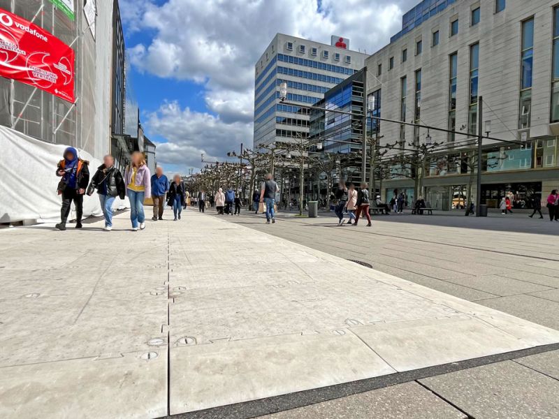 Der Steinboden einer Fußgängerzone ist mit Kunststoffplatten bedeckt. Man sieht große Gebäude im Hintergrund.