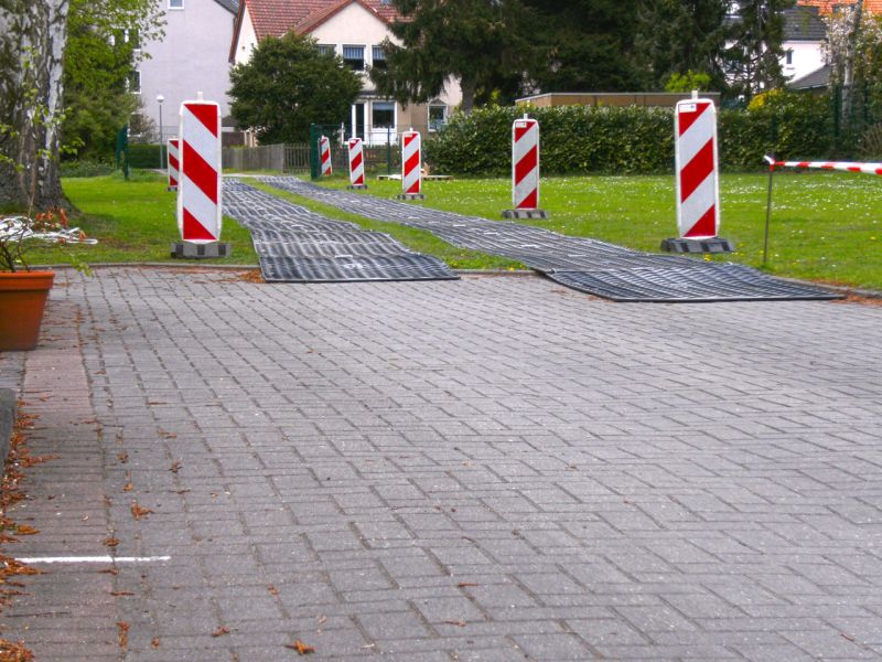 Übergang von Pflaster zu provisorischem Fahrweg über eine Wiese.