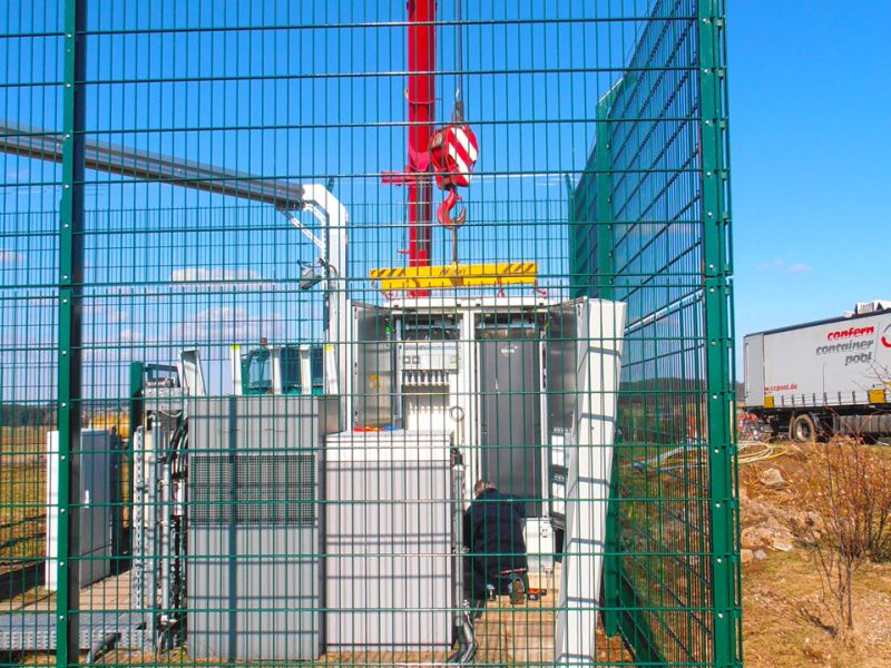 Teleskopkran hebt Container mithilfe von Bodenschutzplatten auf unebenem Gelände