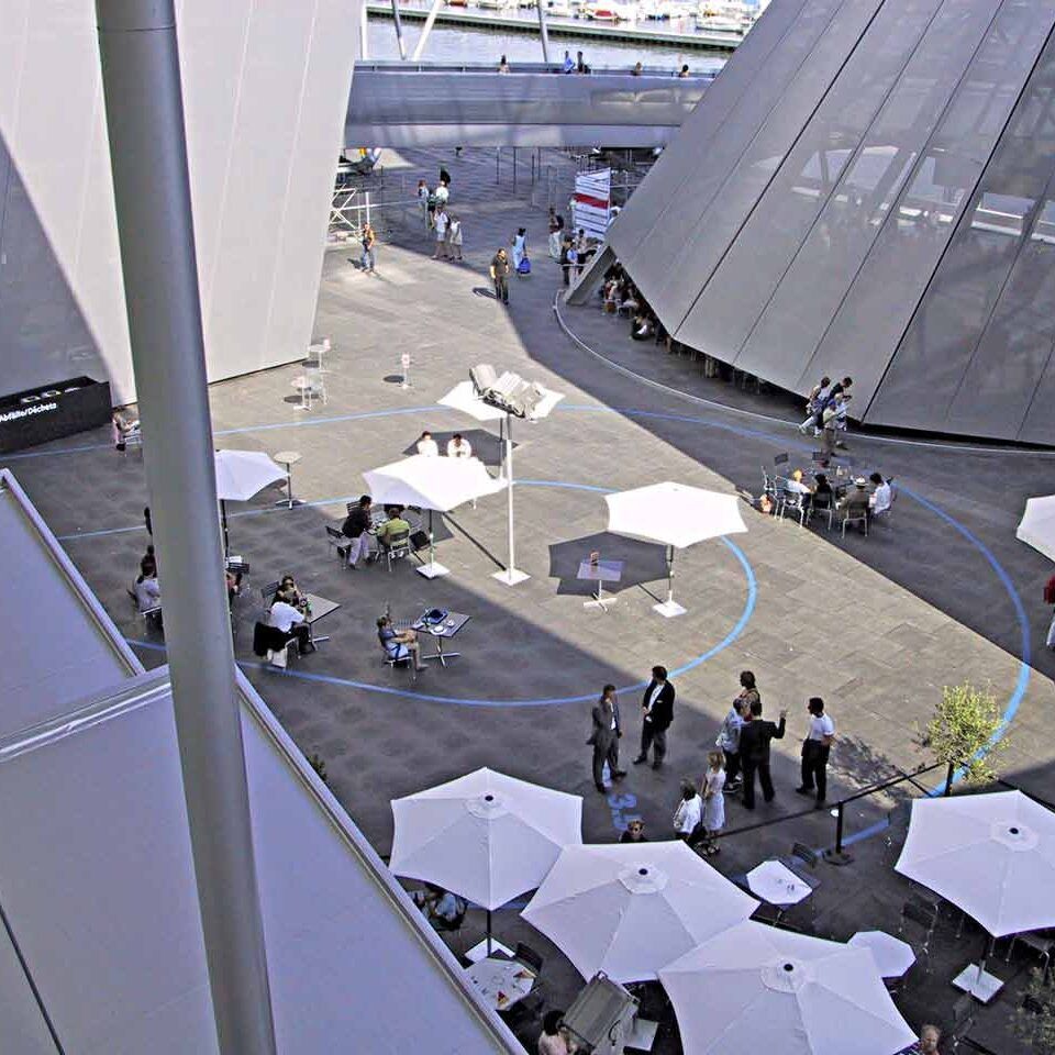 Blick von oben auf eine Eventfläche aus Bodenmatten. Sonnenschirme, Tische und Personen befinden sich darauf.