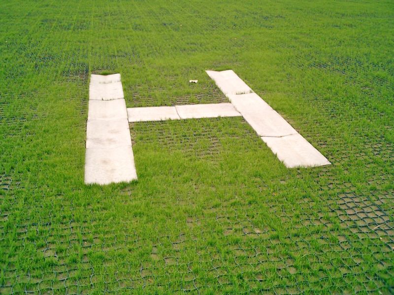 H Markierung auf einer mit Bodengittern befestigten Rasenfläche.