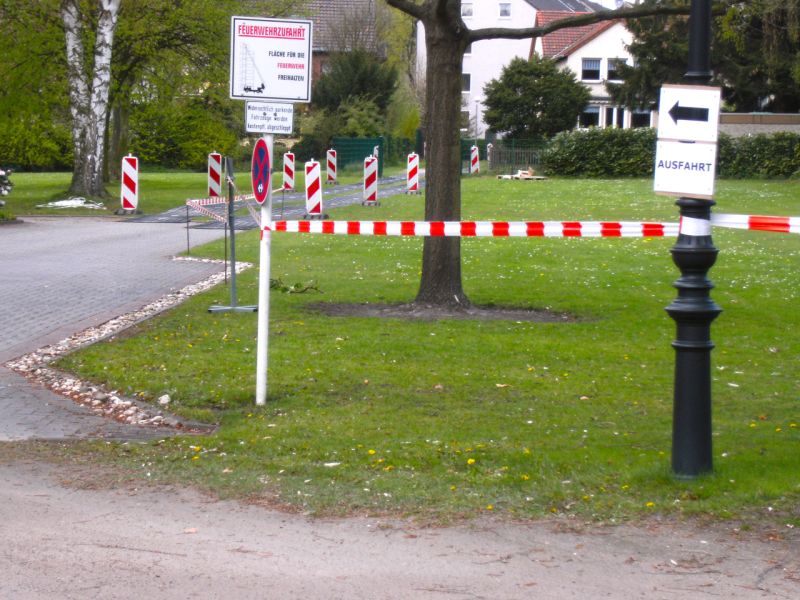 Absperrbänder und Leitbaken markieren vorübergehende Verkehrsführung im Grünbereich.