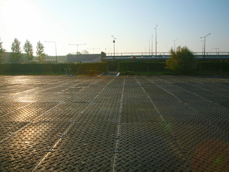 Weitläufige befestigte Fläche mit strukturierter Oberfläche bei tiefstehender Sonne.