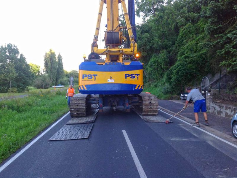 Bohrgerät fährt über versetzte Kunststoffplatten auf Asphaltstraße.