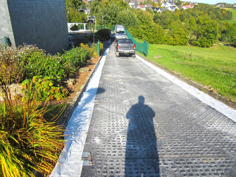 Fahrzeuge nutzen eine ausgelegte Kunststofframpe auf einer Steigung, die sicheren Zugang zum Einsatzgebiet des Mobilkrans schafft.