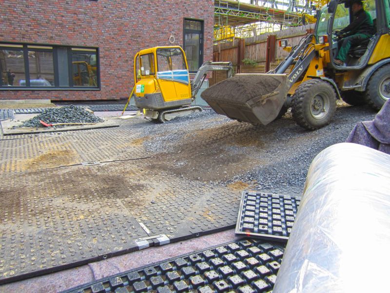 Radlader und Minibagger arbeiten gemeinsam auf gesicherter Dachfläche