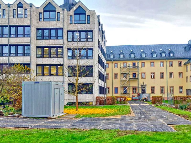 Auf einer Baustelle im Gerüstbau wurden Fahrplatten auf dem Rasen vor 2 Gebäuden verlegt