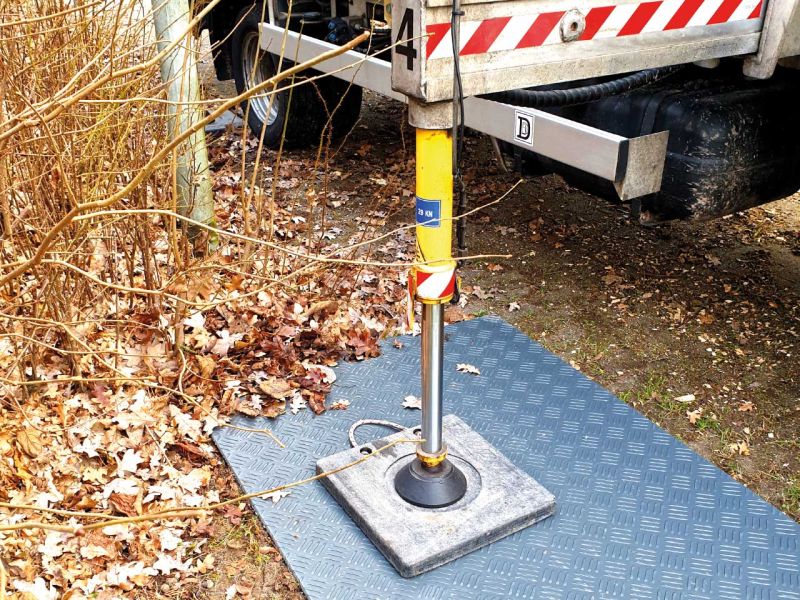 LKW-Kran mit stabilisierenden Abstützplatten und Lastverteilplatten auf dem Boden.