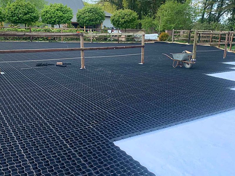 Bodengitter aus Kunststoff liegen auf einem Trennvlies in einem Paddock