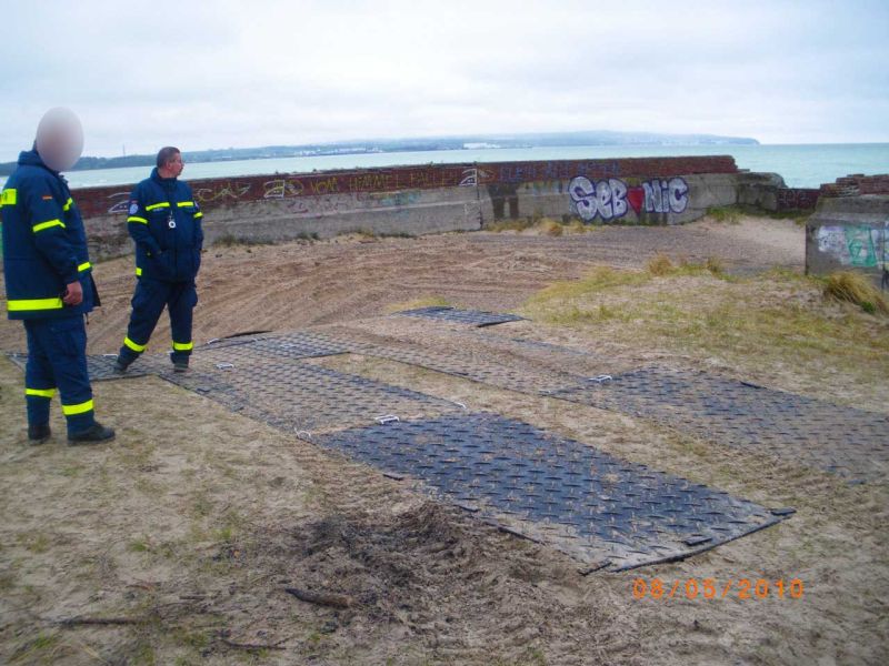 Bodenschutzplatten bilden sichere Spuren über losen Sand am Strandbereich.