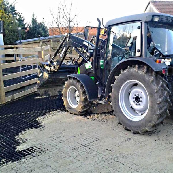 Ein Traktor kippt Sand auf neu verlegte Bodengitter.