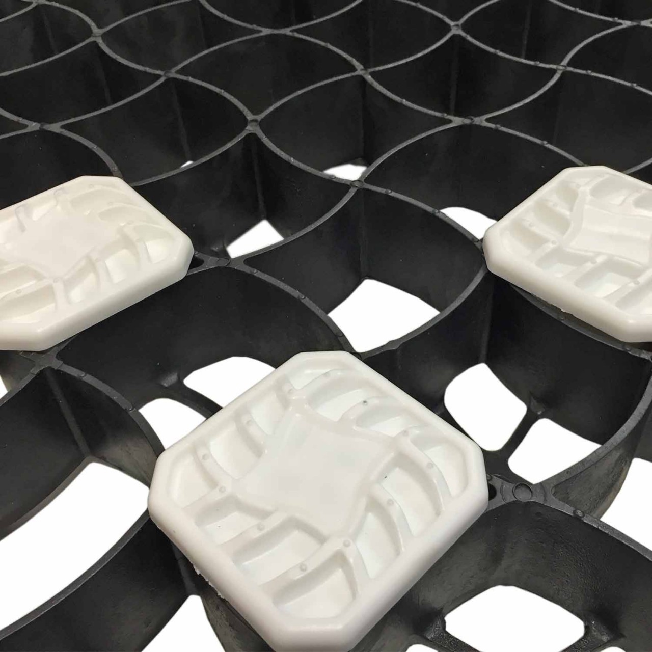 Detailaufnahme einer schwarzen Kunststoff-Gittermatte mit weißen Abstandshaltern zur Stabilisierung und Befestigung von Flächen.
