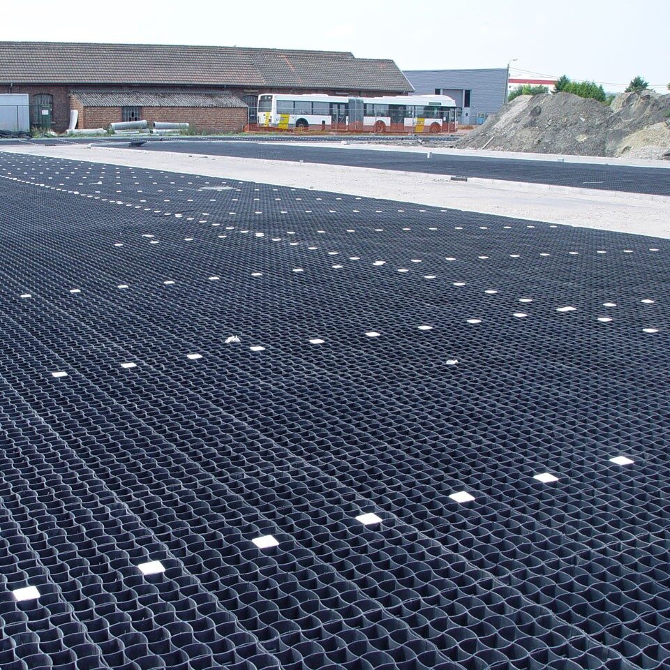 Großflächig verlegte schwarze Gittermatten mit rutschfester Struktur zur Stabilisierung und Befestigung von Verkehrs- oder Lagerflächen.