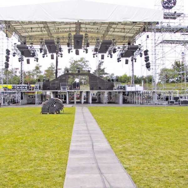 Bodenmatten als Stagemats verlegt auf dem Rasen vor einer Bühne bei einem Open-Air-Event