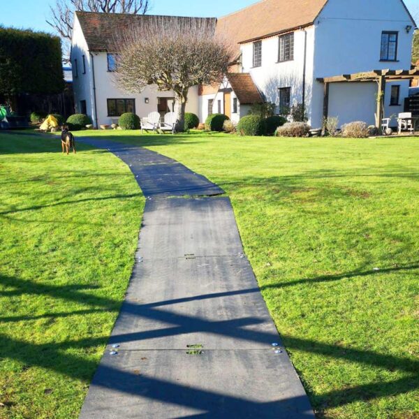 Die e:tek MIN EVO als Fahrspur verlegt auf einer Rasenfläche in einem Garten.
