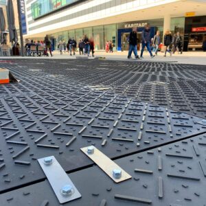 Detailaufnahme von Bodenschutzplatten mit Metallverbindern auf einer Baustelle in der Fußgängerzone.