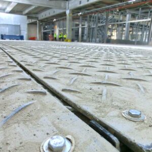 Verschraubte Bodenschutzplatten bilden eine stabile, rutschfeste Arbeitsfläche in einer Industriehalle.