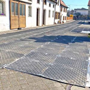 Bodenschutzplatten bilden eine stabile, temporäre Fahrbahn durch eine Wohnstraße während Bauarbeiten.
