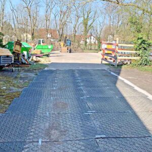 Verlegte Bodenschutzplatten schaffen eine stabile Zufahrt für Fahrzeuge und Maschinen auf einer Baustelle.