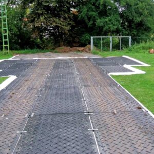 Bodenschutzplatten bilden eine stabile Fahrstraße über eine Rasenfläche, ideal für Fahrzeuge und Maschinen.