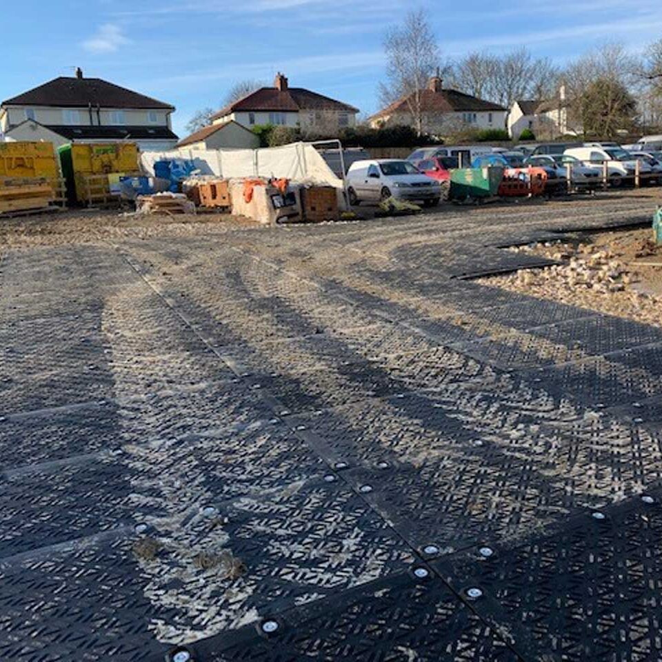 Eine mobile Baustraße und Parkfläche aus Kunststoffplatten auf einem Schotteruntergrund. Mehrere Fahrzeuge sind geparkt.