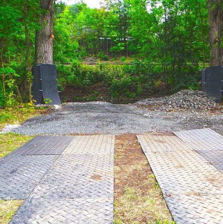 Bodenschutzplatten bilden eine stabile Fahrspur durch bewaldetes Gelände und schützen den Untergrund.