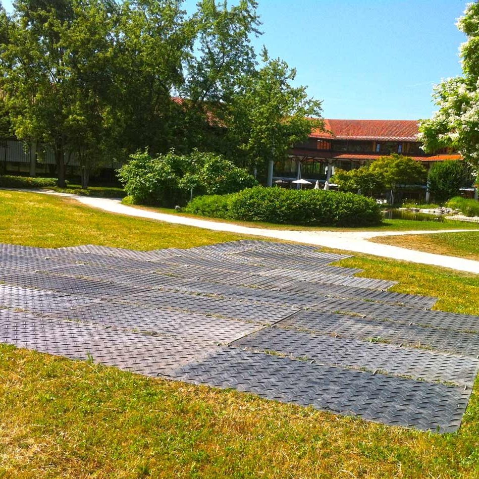 Bodenschutzplatten bilden eine stabile Arbeits- und Stellfläche auf einer gepflegten Rasenfläche.