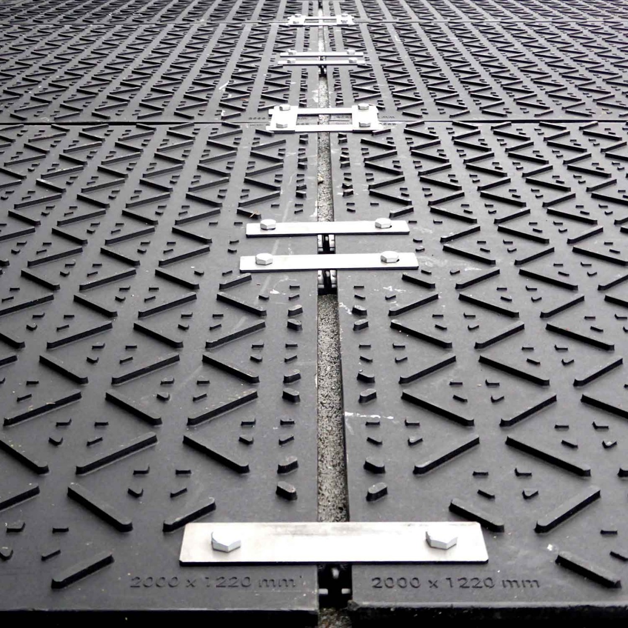 Bodenschutzplatten sind mit Stahlverbindern verschraubt und bilden eine gleichmäßige, stabile Fläche.