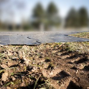 Nahaufnahme von Fahrspuren auf einer Wiese. Im Hintergrund sind die Scobaplate Bodenschutzplatten erkennbar.