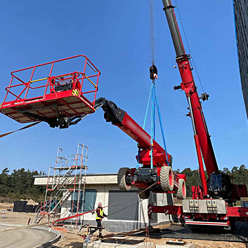 Mobilkran hebt Arbeitsbühne auf stabilisierter Fläche mit Kunststoffplatten im Baustelleneinsatz
